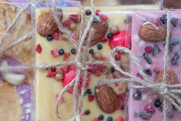 A set of various chocolates white, pink, brown, bitter, milk wrapped in a transparent package with a jute rope bow.