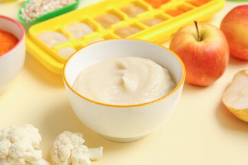 Bowl with healthy baby food on color background, closeup