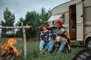 Couple in a checkered plaid roasting marshmallows on fire near the trailer home.