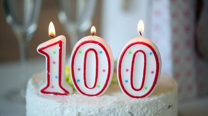 Birthday candle as number one hundred on top of sweet cake on the table, 100th birthday
