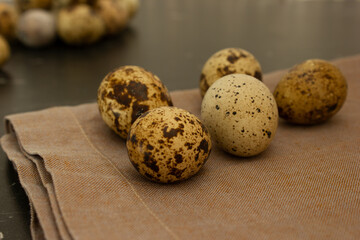 Close-up of quail eggs lie on a napkin, against the background of other eggs.