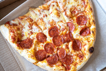 Family pizza, half of oval, consists of two types, margarita, pepperoni. Food delivery concept, takeaway, Italian cuisine, fast food, togetherness. Top view, flat lay, close-up. Authentic lifestyle