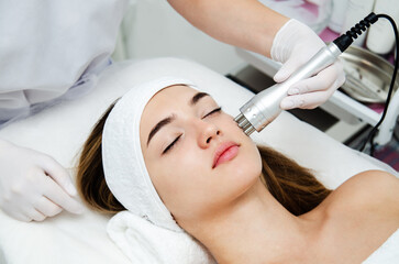 Woman getting beauty treatment in medical spa center. Skin care and rejuvenation concept. Beautician holding apparatus near the face. - 419638572