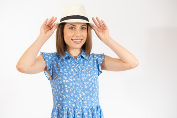 Beautiful young woman laughing woman in blue dress and straw hat looking happy over white background