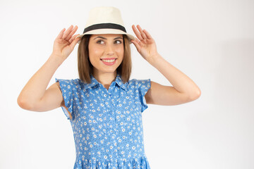Beautiful young woman laughing woman in blue dress and straw hat looking happy over white background