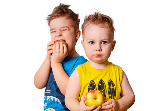 Two lovely boys eating apples. Cute children on the white background, isolated picture.