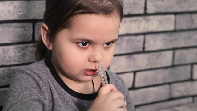 Little girl using baby nasal aspirator. Mucus and snot suction.