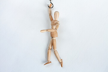 a wooden mannequin hanging on a hook on white background