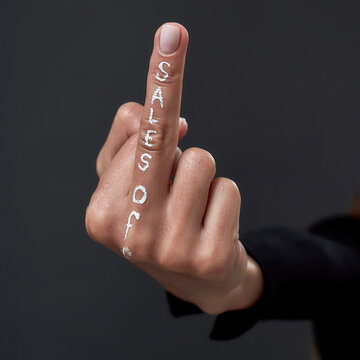 Hand of woman with middle finger and sales off writing
