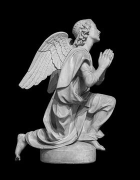 Angel statue isolated on black background. White stone sculpture of praying cherub