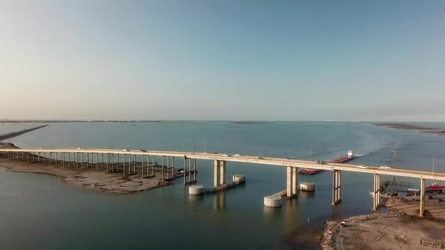 Expansive aerial view of  large barge traveling under the JFK Causeway at Corpus Christi Bay along the Intercoastal Waterway in Texas