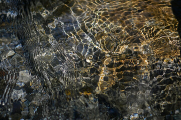 Closeup of restless surface of a mountain stream. Abstract water surface. Macro photography.