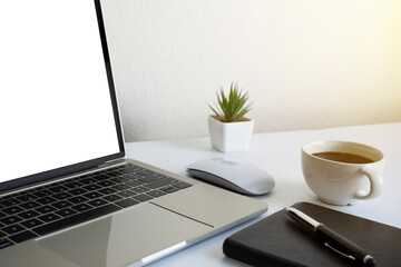 Fototapeta premium Laptop computer blank screen on white office desk table with coffee cup and notebook, mouse computer with equipment office supplies. Business and finance concept. Workplace, Flat lay with copy space.
