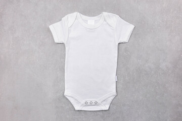White baby girl or boy bodysuit mockup on the gray concrete background. Design onesie template,...