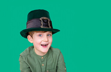 A closeup portrait of smiling preteen boy in carnival St. Patrick's Day hat on green backgroundwhite. Copy space.