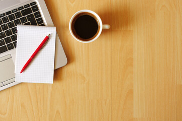 Work from Home. Office set with laptop, notebook, coffee cup, pen on wooden table. Business concept. Flat lay top view copy space.