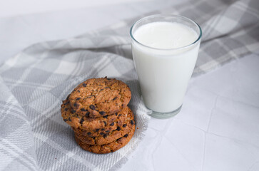 A glass of milk and a stack of homemade oatmeal cookies on a light white background. The concept of proper nutrition. Breakfast in the village. copy space for text. top view