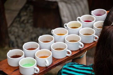 a woman holding a dish of cups of colorful coffee and drinks