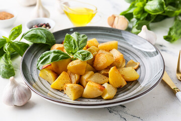 Plate of tasty baked potato with garlic on light background