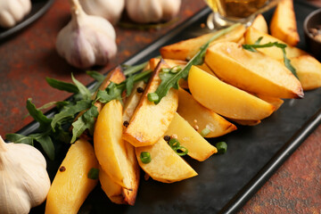 Plate of tasty baked potato with garlic on grunge background
