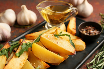 Plate of tasty baked potato with garlic on grunge background