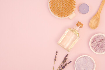 The concept of skin and body care at home. Dry brush massage, natural homemade body scrub with lavender and sea salt, body oil. Body cosmetics on pink background with copy space, top view, flat lay
