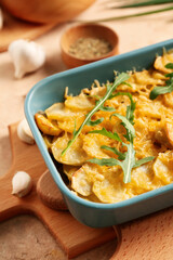 Baking dish of tasty potato with cheese and garlic, closeup