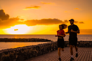 Fototapeta na wymiar Runner athletes running at seaside. Fit runner fitness runner during outdoor workout with sunset background.