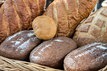 Fresh bread are in a basket. A few loaves of tasty bread on counter on street, assortment.
