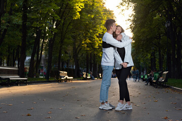 Happy young couple hugging in park. Full size portrait. First date