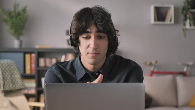 customer care employee works from home gives assistance to client,young entrepreneur male in headset sits at the desk has job interview,business man talks at the laptop video meeting conference call