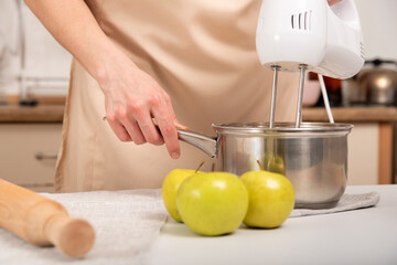 Mixer mixes the ingredients in saucepan. Cooking an apple pie.