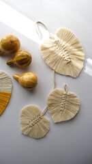Leaf macrame made of green, white and yellow thread on a white background. Yellow, white and yellow macrame threads.