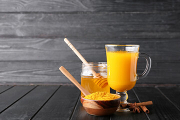 Composition with cup of healthy turmeric drink on dark wooden background
