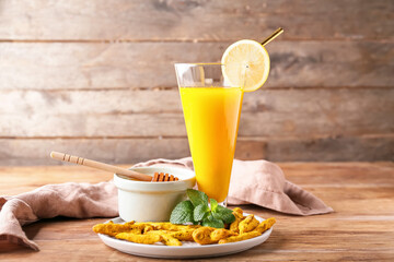 Fototapeta premium Glass of healthy turmeric drink on wooden background