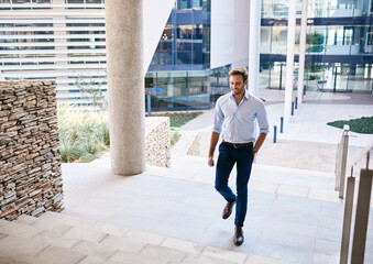 Young businessman smiling while walking up stairs outside of an office
