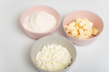 Three plates with flour, cottage cheese and butter. Pie making process.