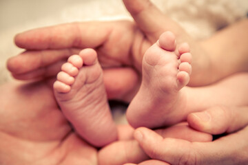 Parents holding the feet of their newborn baby...