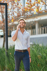 Smiling businessman talking on his phone while walking outside