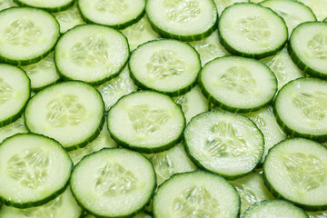 Fresh green slices of cucumber as background.