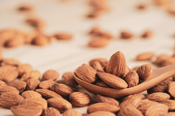 Almonds nut in wooden spoon and pour on table with copy space. Almonds nut is healthy diet food which high protein low fat and essential amino acid.