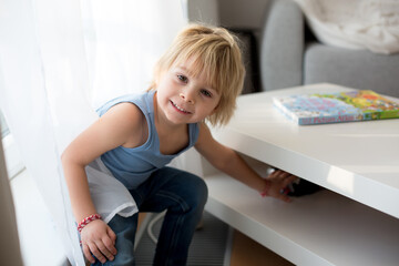 Cute blond toddler child, playing with big toy car