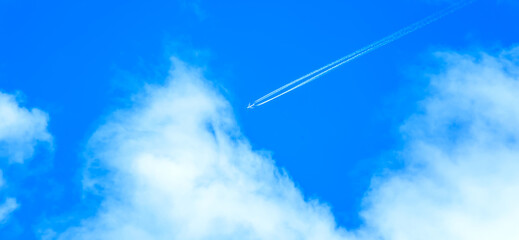 Jet plane in high flight with vapor trail. Airliner flying towards the cloud in blue sky....