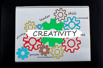 Creativity concept. View of colorful drawing of gears in notepad with different colors pens with creativity inscription.