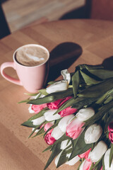 Cup of coffee and a bouquet of white and red tulips on the table. Happy mothers day.