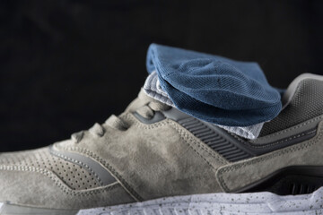A pair of men's cotton socks lies on a gray leather sneaker, close-up.
