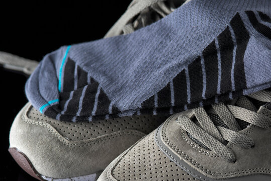 A pair of men's cotton socks lies on a gray leather sneaker, close-up.