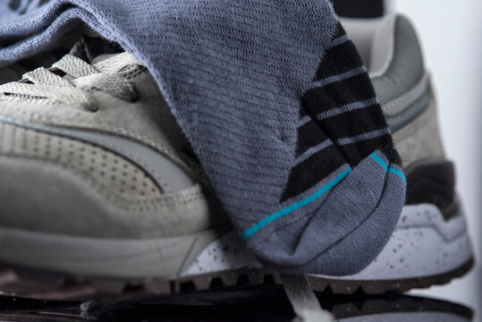 A pair of men's cotton socks lies on a gray leather sneaker, close-up.