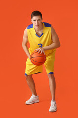 Handsome young man playing basketball on color background