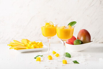 Glasses of mango margarita on light background